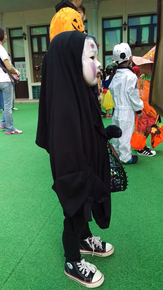 Chỉ nhìn qua thôi cũng đủ thấy tạo hình của "Quỷ Vô diện phiên bản nhí" đã là vô cùng ấn tượng. Cô bé khoảng 4 tuổi trùm một bộ đồ màu đen từ dài đến đầu gối, phần mặt được tô vẽ trắng bệch, cộng thêm những vệt màu tím kỳ dị tạo ra vẻ đáng sợ nhưng cũng rất hài hước. Tay cô bé cầm một chiếc giỏ xách, chân lại đi giày vải... tất cả đều màu đen kết hợp với khuôn mặt "ngố tàu" tạo ra vẻ ngoài kỳ dị khiến các em nhỏ khác cũng phải sợ hãi.