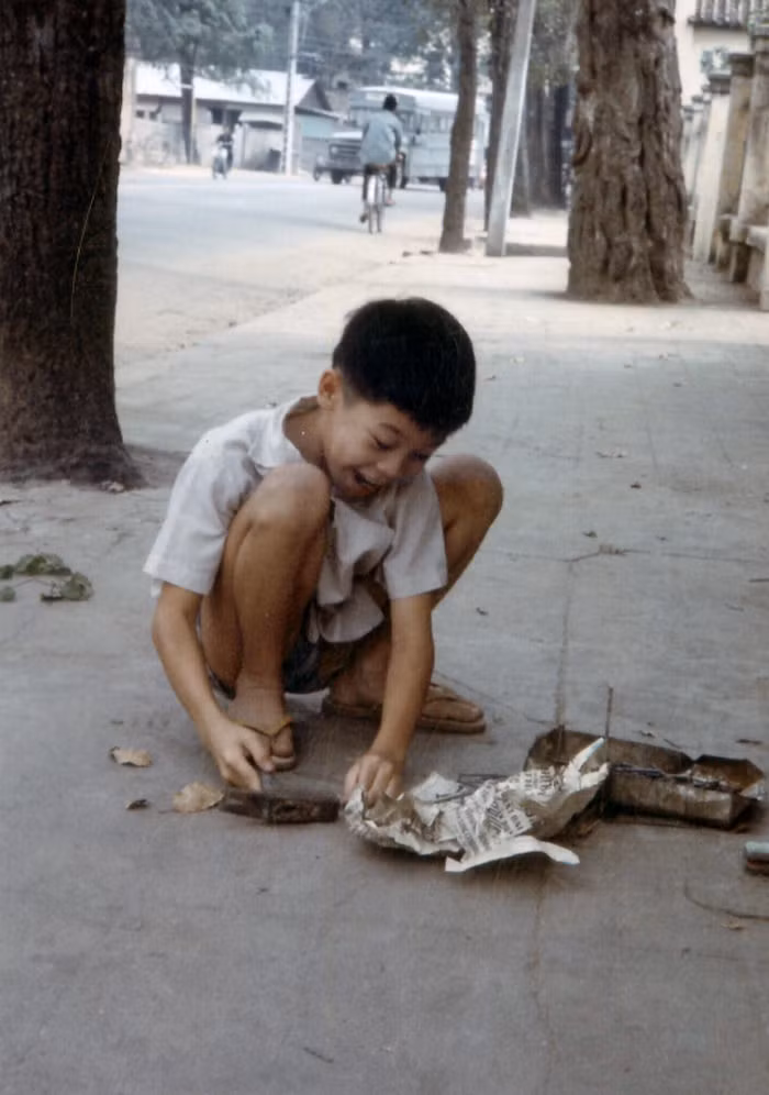 Cậu bé nghịch búa và đinh trên vỉa hè.