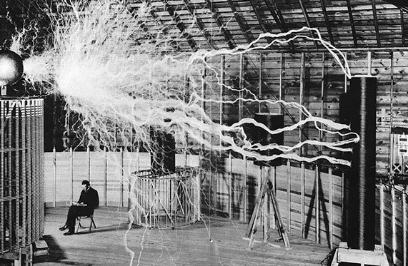 Nhà khoa học Nikola Tesla ngồi làm việc trong phòng thí nghiệm năm 1899. Trong căn phòng này có máy phát phóng đại - thiết bị mà Tesla tìm cách khai thác sức mạnh của cuộn dây Tesla để tạo ra nguồn điện không dây.