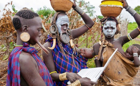 Phụ nữ ở bộc lạc Ethiopia vừa đội giỏ trên đầu vừa sử dụng máy tính xách tay. Ảnh: Dailymail.