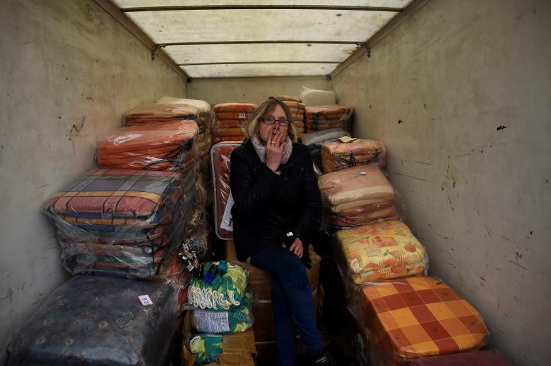 Người phụ nữ ngồi hút thuốc trong xe tải chở đầy những chiếc đệm.