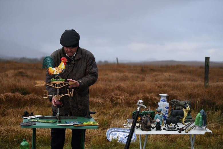 Người đàn ông bày một số đồ cổ và đồ trang sức bán bên lề đường.