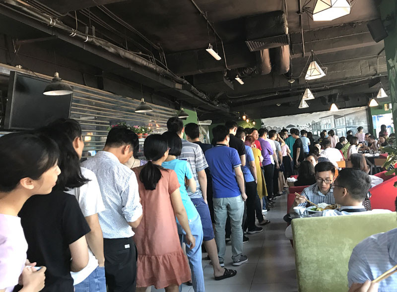 Tại một quán cơm có điều hòa, khách xếp hàng dài cả hơn chục mét để chờ cơm.