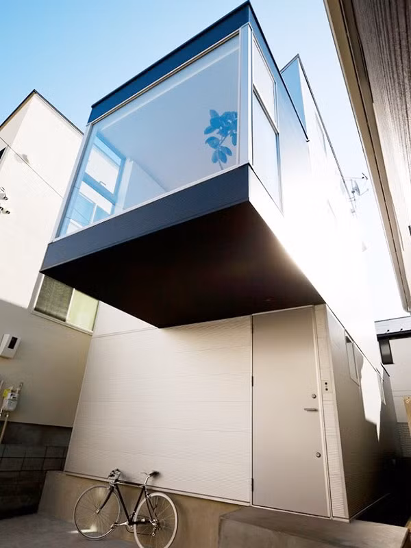 Tầng 2 được thiết kế thêm phần ban công, xung quanh được lắp đặt kính trong suốt, vừa để mở rộng diện tích một cách tối đa, vừa giúp ánh sáng tràn ngập vào mọi góc nhỏ trong không gian. Cách tạo ban công vươn ra phía trước cũng là giải pháp giúp tạo mái hiên che mưa nắng cho tầng 1.