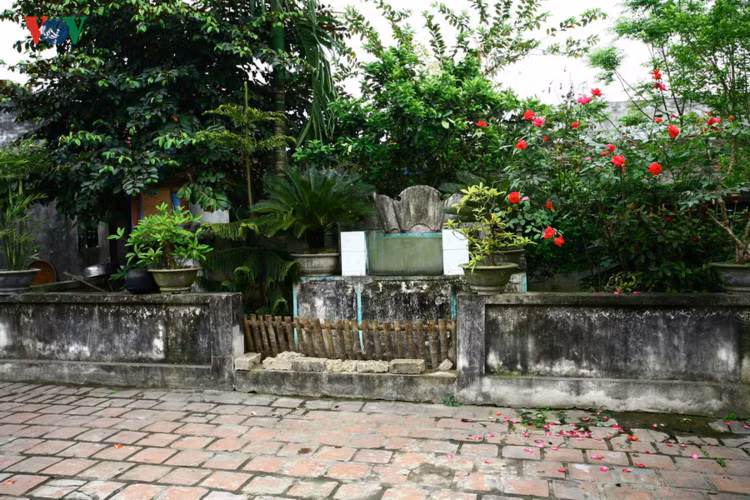 Phía trước ngôi nhà, qua lớp sân là bể nước và bình phong hình cuốn thư nằm trong vườn.