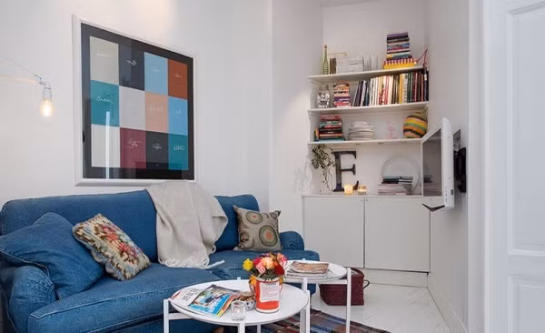 Bên cạnh bếp nấu là phòng khách. Khoảng diện tích không rộng lắm bên trong của căn hộ được dành cho chức năng tiếp khách và sinh hoạt chung của gia đình. Khoảng không gian nho nhỏ ấy được bài trí khá ấn tượng với sofa xanh êm ái, thêm bàn trà nhỏ xinh cho góc chức năng đẹp cá tính.