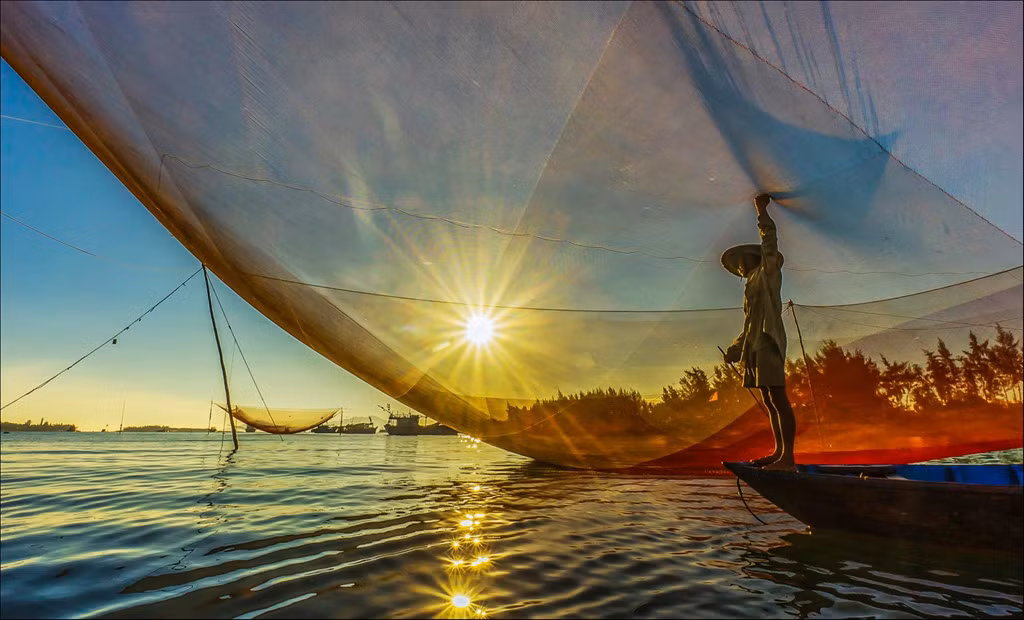 Đến biển Cửa Đại (Quảng Nam), du khách nên đi đón bình minh trên cửa biển và xem ngư dân bắt cá bằng rớ. Những chiếc rớ được làm bằng một tấm lưới lớn, rộng khoảng 80-130 m2, lung linh trong ánh nắng tạo nên một cảnh đẹp nên rất thơ. Ảnh: Lê Thị Minh Nguyệt.