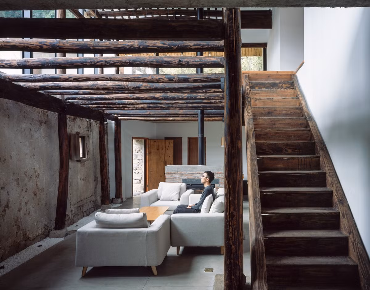 Phòng khách mang hai phong cách, cổ điển và hiện đại. Một bên là tường đất, một bên là tường gạch.