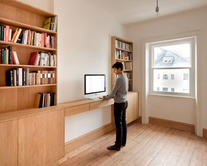 Từ phòng khách có thể nhìn sang không gian nấu nướng, nơi được thiết kế hệ thống tủ ốp cho toàn bộ diện tích tường. Tủ gỗ kết hợp hài hoà với vách ngăn tổ ong bằng gỗ và sàn gỗ mang đến vẻ đẹp ấm cúng, thân thiện cho căn hộ nhỏ.