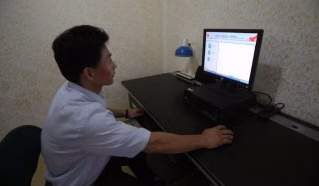 Phòng làm việc đơn sơ gồm một chiếc đèn và một máy vi tính.