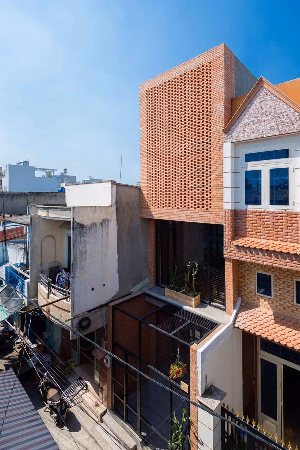  Nhà gạch thô Wasp House tại quận Tân Bình, TP HCM nổi bật lên giữa khu phố với cổng và hàng rào bằng lưới tản nhiệt kim loại.