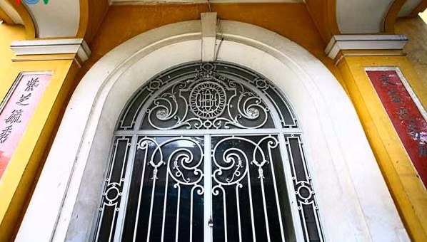 Cửa chính vào sảnh là sự kết hợp Đông - Tây thú vị với chi tiết vòm cuốn và hoa sắt của châu Âu. Hai bên cửa là câu đối chữ Hán đậm nét phương Đông. Ảnh: Vov.