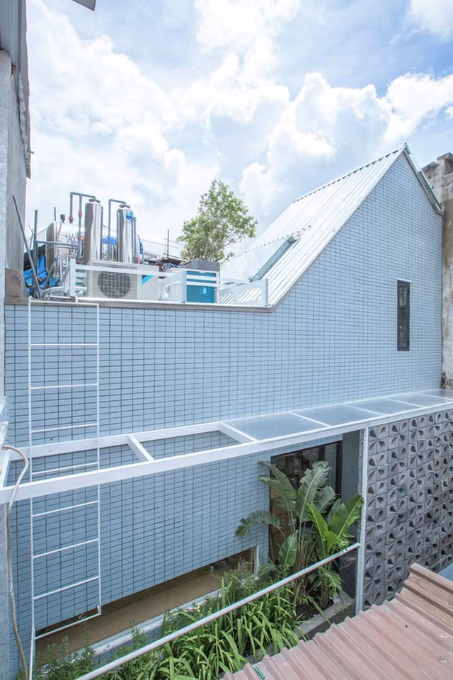 Dù nhỏ, nhưng căn nhà vẫn có được không gian xanh nhờ những hộp cây từ ban công tầng trên. Phần còn lại của ban công được giấu sau bức tường bê tông hình khối. Tấm màn che cứng này cho phép ánh sáng đi vào bên trong nhưng che khuất tầm nhìn từ hàng xóm lân cận.