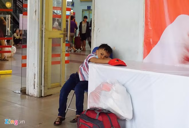 Cậu bé mệt mỏi ngồi trông hành lý cho cha mẹ.