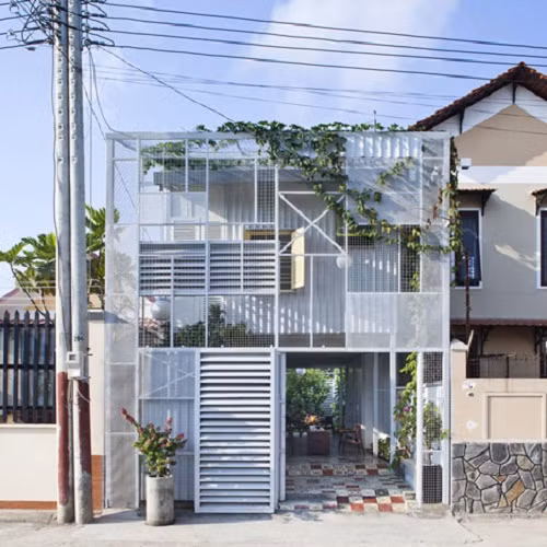 Ngôi nhà “The Nest” tại Bình Dương được báo Tây khen hết lời bởi bên ngoài lạ mắt giống như một lớp “xuyên thấu” nhờ giàn khung và tấm lưới bao quanh. Tầng trệt sát đất được thiết kế mở, phòng khách, phòng bếp thông suốt với khu vườn nhỏ phía ngoài. Ảnh: Deezen.