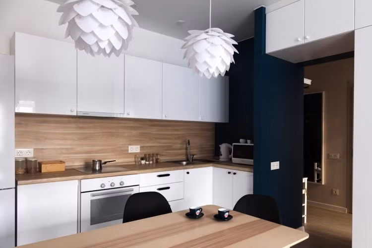 Cánh cửa màu xanh thẫm tương phản với tông màu trắng tạo khu vực bếp một không gian thú vị.