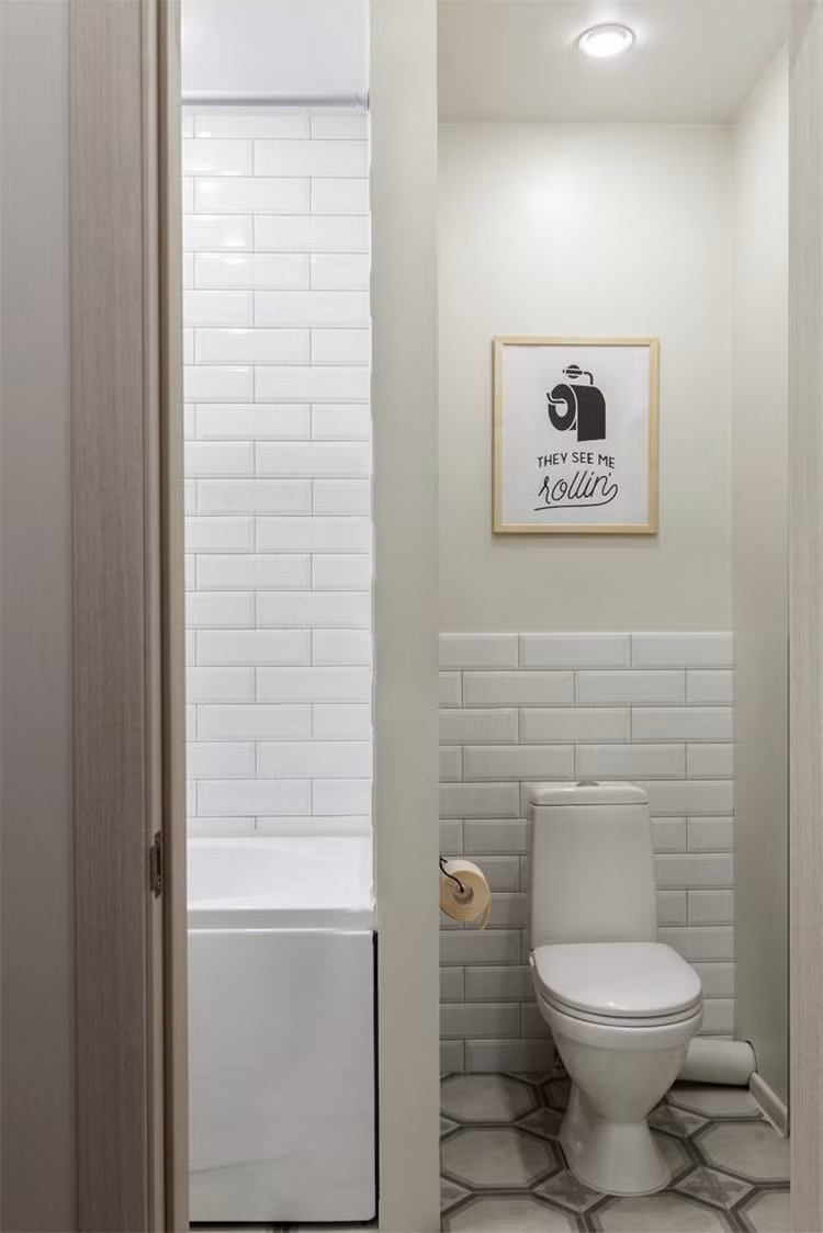 Phòng tắm nhỏ có tường ngăn cách giữa bồn cầu và bồn tắm.