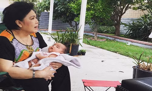 Mẹ chồng cô ẵm bé Yvona đang ngủ say sưa ra hiên nhà, hít thở không khí trong lành.