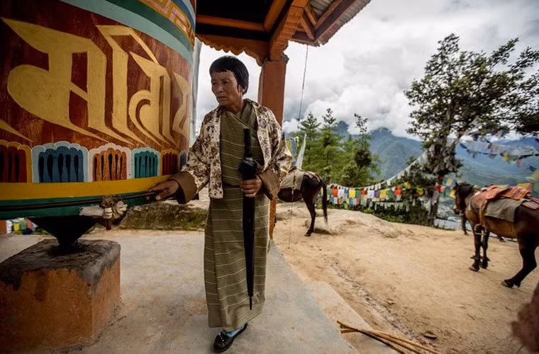 Cụ bà hành hương tới chùa Taktsang đang dừng chân tại bánh xe cầu nguyện.