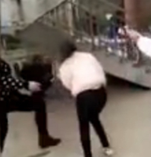 Nữ sinh (áo hồng) bị một số cô gái dùng chân đạp tới tấp (Ảnh cắt từ clip).