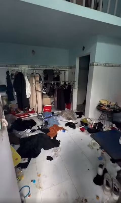 Đồ đạc và rác được quăng bừa, chất đống lên từ cửa phòng, vương vãi khắp sàn nhà, vứt đầy trên cả chỗ ngủ lẫn bàn trang điểm. (Video: Quỳnh Miên)