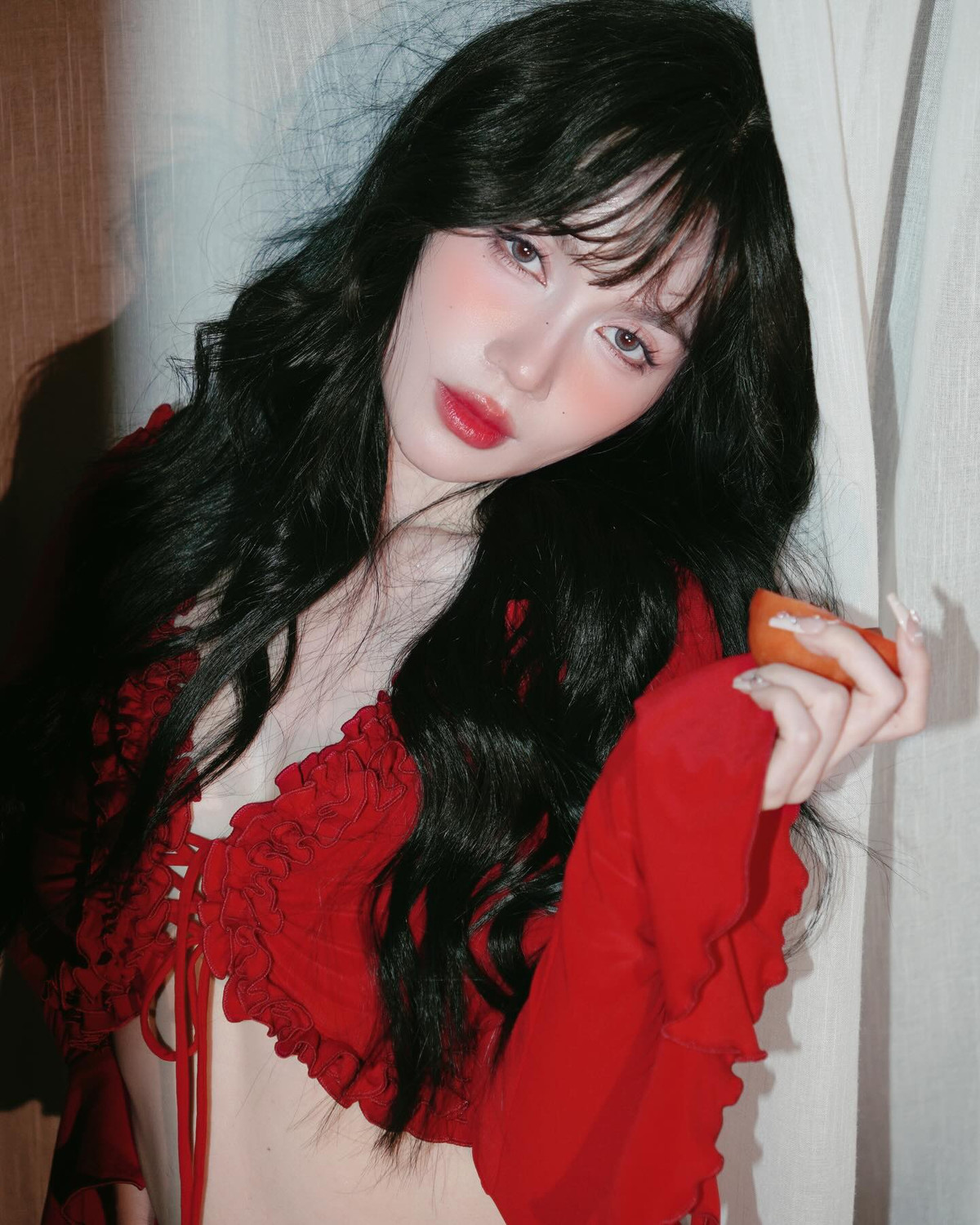 Lấy cảm hứng từ sắc đỏ rực rỡ của quả cà chua, cô chọn tông đỏ chủ đạo, kết hợp cùng mái tóc đen uốn xoăn bồng bềnh, tạo nên vẻ đẹp vừa huyền bí vừa quyến rũ.