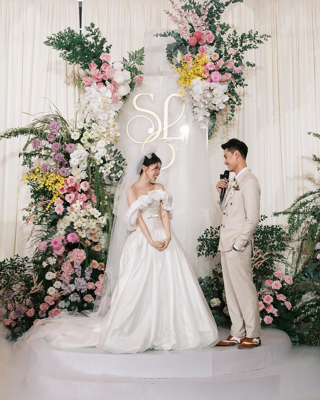 Trong ngày cưới, Ly Phạm chọn bộ váy cưới thiết kế riêng với các chi tiết đính kết tinh xảo, tôn lên vẻ đẹp yêu kiều. Cô xây dựng tạo hình cổ điển, diện mẫu váy cưới trắng trễ vai, dáng bồng xòe, chất liệu satin.