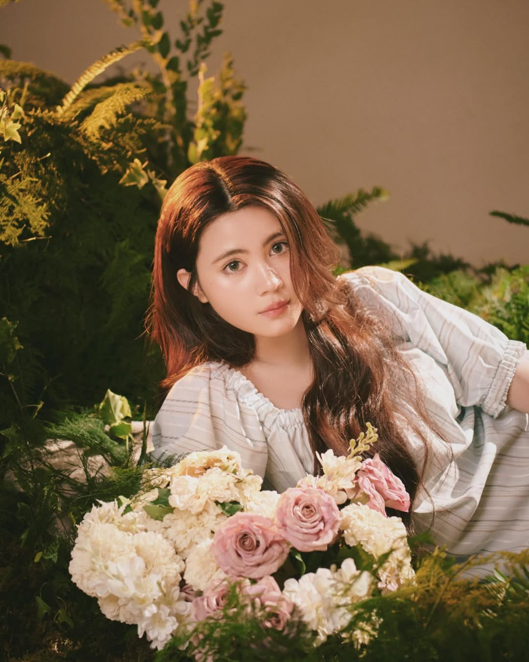 Cô nàng lựa chọn background thiên nhiên thơ mộng, xung quanh là cây xanh và hoa lá, tạo cảm giác vừa thanh lịch vừa dịu dàng.