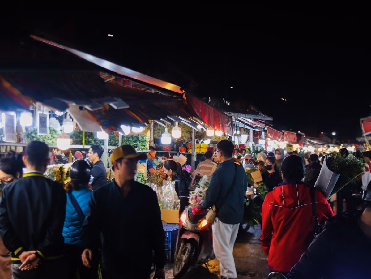 Dù đồng hồ đã điểm 12h đêm, tại chợ hoa Quảng An (quận Tây Hồ, Hà Nội) vẫn rộn ràng tiếng mời chào mua bán của các tiểu thương. Người dân địa phương cho biết, cứ mỗi dịp 8/3 hằng năm, chợ lại trở nên nhộn nhịp hơn bao giờ hết, thu hút đông đảo mọi người đến mua hoa. Trong ảnh là không khí mua bán tấp nập tại chợ hoa Quảng An về đê