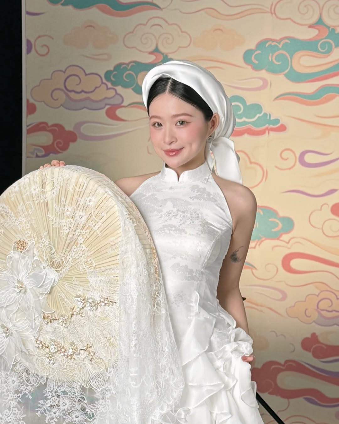 Thiết kế yếm trắng mang vẻ đẹp thanh lịch, dịu dàng nhưng đầy cuốn hút. Chiếc khăn lụa đội đầu kết hợp với quạt ren giúp Chao trông như một nàng tiểu thư đài các của thời xưa.