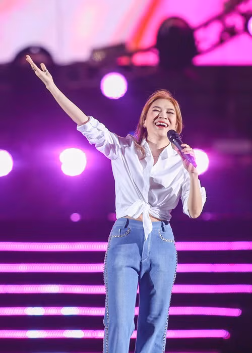 Nữ ca sĩ trẻ trung, năng động với quần jean, áo sơ mi.