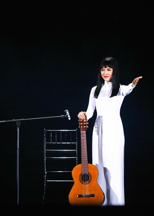 Mỹ Tâm diện áo dài trắng khi chơi đàn guitar.