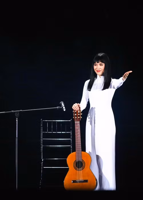 Mỹ Tâm diện áo dài trắng khi chơi đàn guitar.