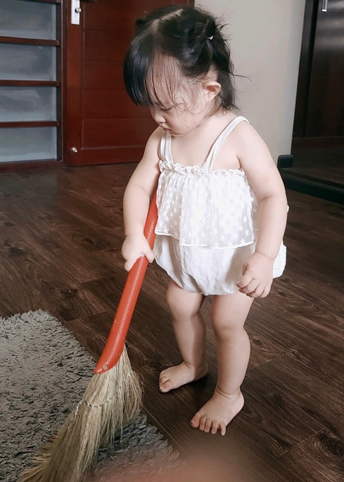 Nhóc tì nhà Ông Cao Thắng cầm chổi chăm chú quét nhà.