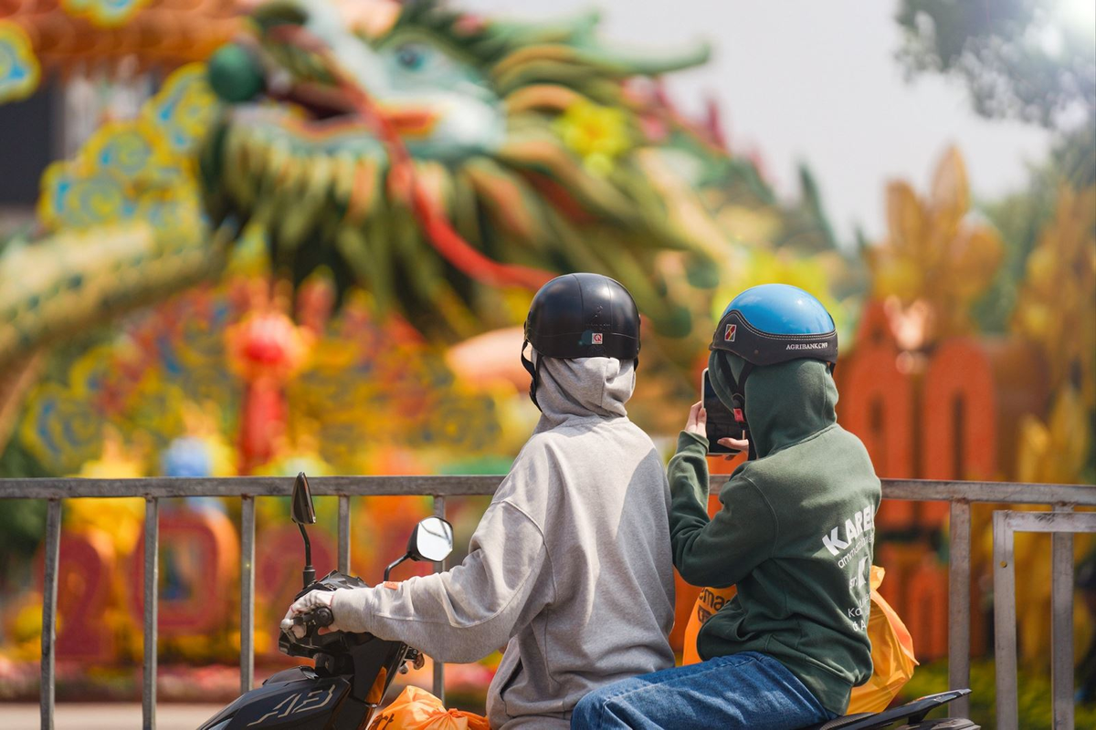 Người dân đi ngang qua đường Nguyễn Huệ, Quận 1 cũng tranh thủ dừng lại chụp ảnh linh vật rồng ngay khu vực cổng chào của đường hoa.