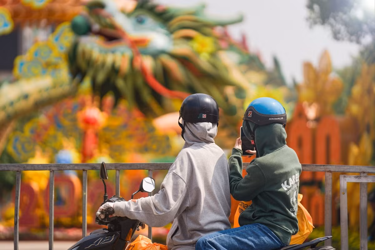 Người dân đi ngang qua đường Nguyễn Huệ, Quận 1 cũng tranh thủ dừng lại chụp ảnh linh vật rồng ngay khu vực cổng chào của đường hoa.