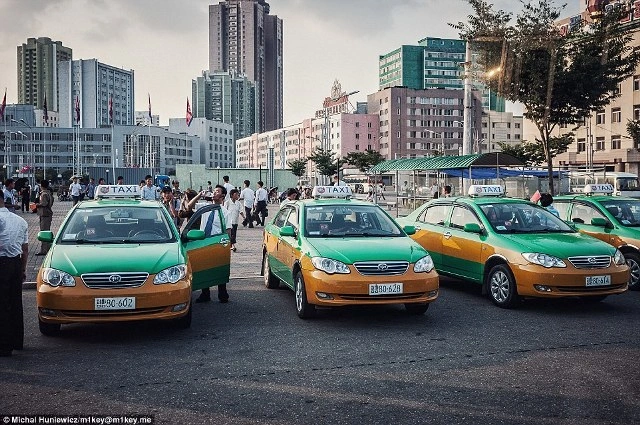 Hỉnh ảnh xe taxi được sơn màu xanh và vàng đồng trong thành phố.