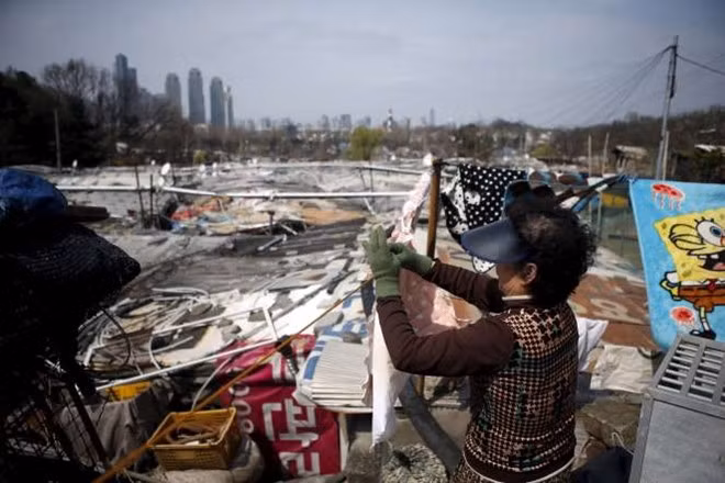 Người dân phơi quần áo tại căn nhà tạm ở khu Guryong, phía xa là các tòa nhà cao tầng sang trọng tại quận Gangnam.