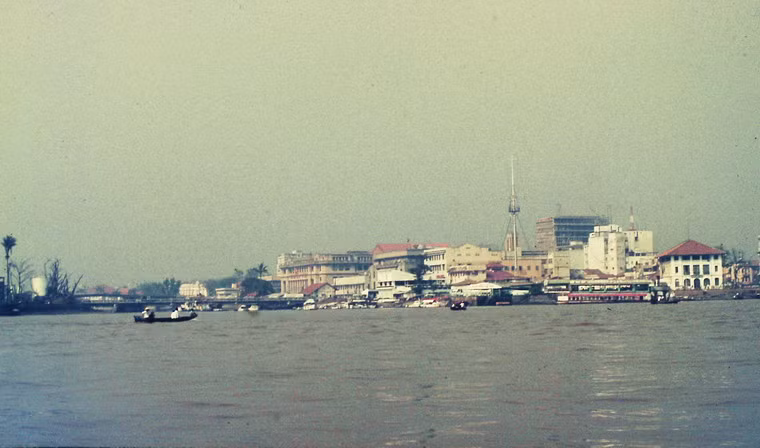 Quang cảnh bờ sông Sài Gòn ở quận 1 nhìn từ một con thuyền, với cột cờ Thủ Ngữ là điểm nhấn.