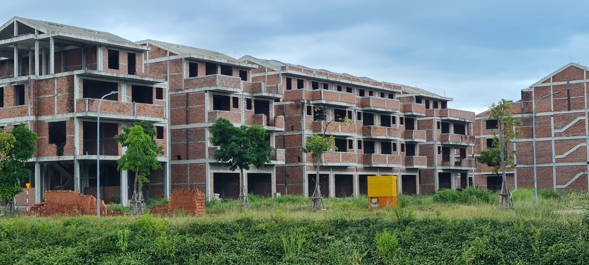 Cỏ dại ngập lối quanh những căn biệt thự chỉ mới được xây thô.