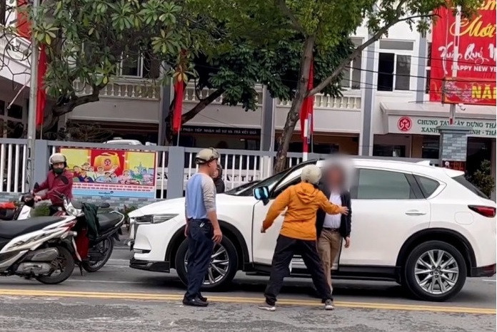 Trước đó, người phụ nữ trên đội mũ bảo hiểm, đeo khẩu trang, đi xe máy dừng đỗ tại đèn đỏ khu vực ngã tư Hoàng Hoa Thám - Nguyễn Trãi. Khi đó, người đàn ông điều khiển xe ô tô màu trắng, đi tới và có chạm nhẹ vào đuôi xe máy khiến người phụ nữ này phản ứng.