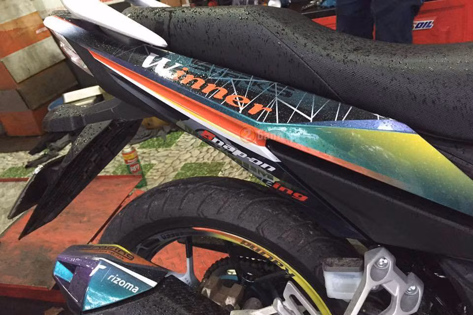 Cánh bửng của xe vẫn thiết kế lại với dòng chữ Winner mang tông màu vàng cam trong khi đó chữ “W” nổi bật màu trắng trên nền xanh đen.