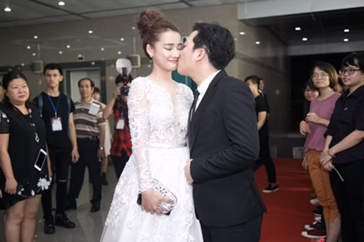 Tháng 1/2017, tại lễ trao giải Mai Vàng lần thứ 22, Trường Giang - Nhã Phương sánh đôi bên nhau. Không chỉ chu đáo nâng váy cho bạn gái, nam danh hài còn hôn cô trên thảm đỏ. (Ảnh: Dân Việt)