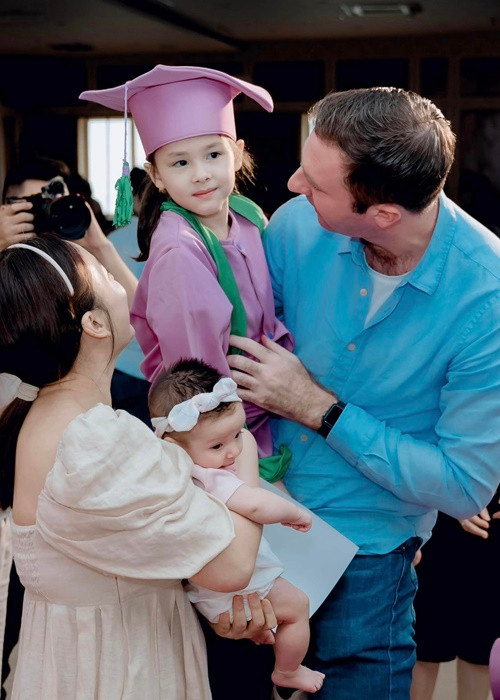 Bé Lina hạnh phúc trong vòng tay bố mẹ và em gái trong lễ tốt nghiệp mầm non.