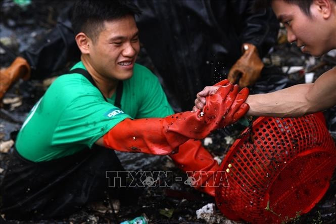 Các thành viên hỗ trợ nhau tìm chỗ đứng để vớt rác ở những vị trí khó khăn dưới dòng sông.