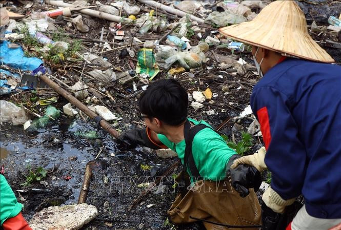 Lượng rác rất dày khiến các thành viên phải dùng cào để kéo rác từ dưới dòng sông.