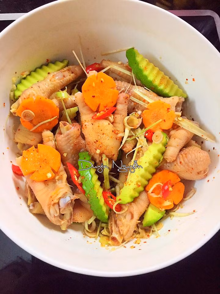 Bước 5: Bỏ chân gà đã ráo nước vào tô lớn cho thêm xoài xanh, quất, tỏi, sả, cà rốt sau cùng đổ hỗn hợp nước mắm đã pha ở trên vào trộn thật đều cho thấm gia vị. 