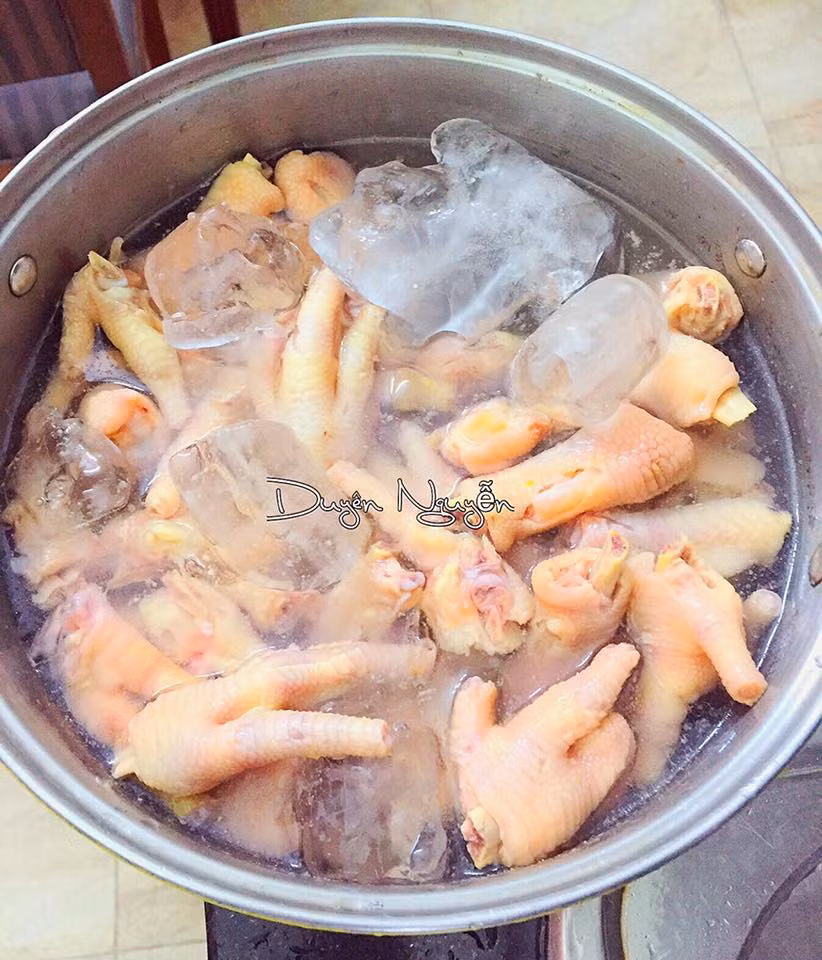 Bước 2: Luộc chân gà, trong khi luộc cho thêm giấm, vài lát gừng và muối vào nồi chờ đến khi chân gà chín tới thì vớt ra và thả ngay vào nước đá ngâm khoảng 10 phút để chân gà được giòn hơn, sau cùng vớt ra để ráo. 