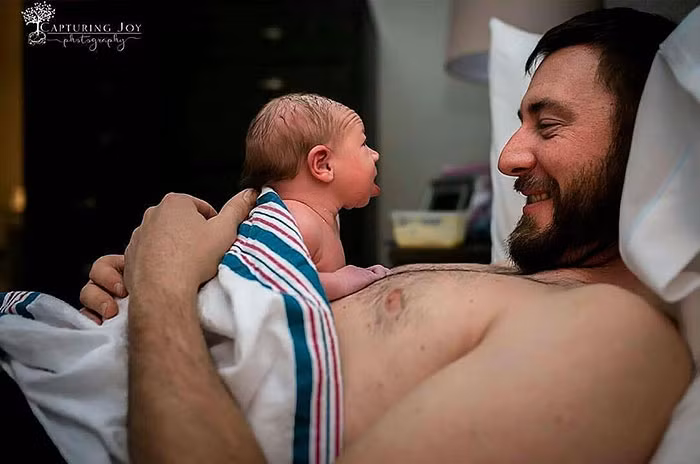 Người cha này không biết rằng khoảnh khắc ngọt ngào nhất trong cuộc đời anh đã được chụp hình ghi lại. Đó là giây phút cô con gái mới sinh lần đầu tiên ngẩng đầu nhìn thẳng vào mắt cha mình.