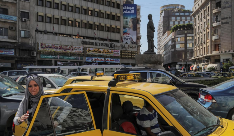 Một người phụ nữ xuống taxi giữa "biển" xe đông đúc ở Damascus. Ảnh: Reuters.
